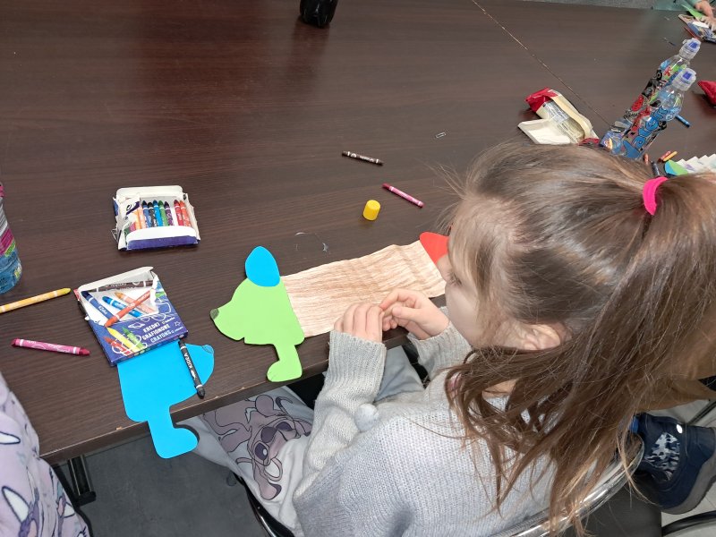 Zdjęcie przedstawia uczestniczkę zajęć siedzącą na krześle przy stoliku w trakcie zajęć plastycznych  