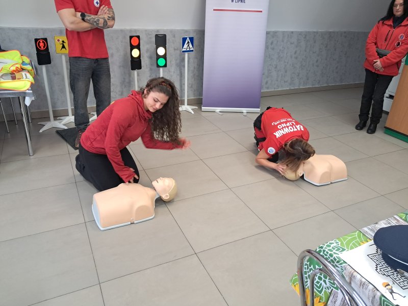 Zdjęcie przedstawia ratowników pokazujących na fantomach jak udzielać pierwszej pomocy.  