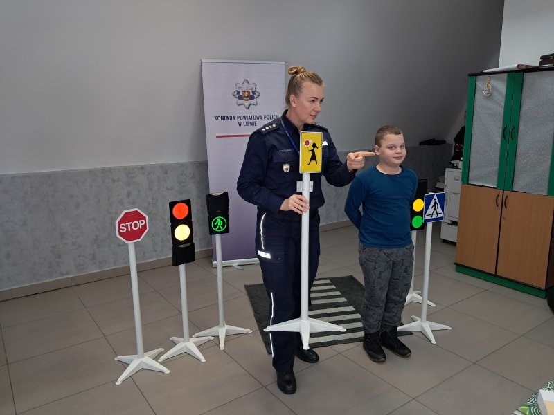 Zdjęcie przedstawia rzecznika prasowego policji Małgorzatę Małkińską i uczestnika zajęć w trakcie scenki sytuacyjnej na zainscenizowanym przejściu dla pieszych w sali, w której odbywały się zajęcia.  