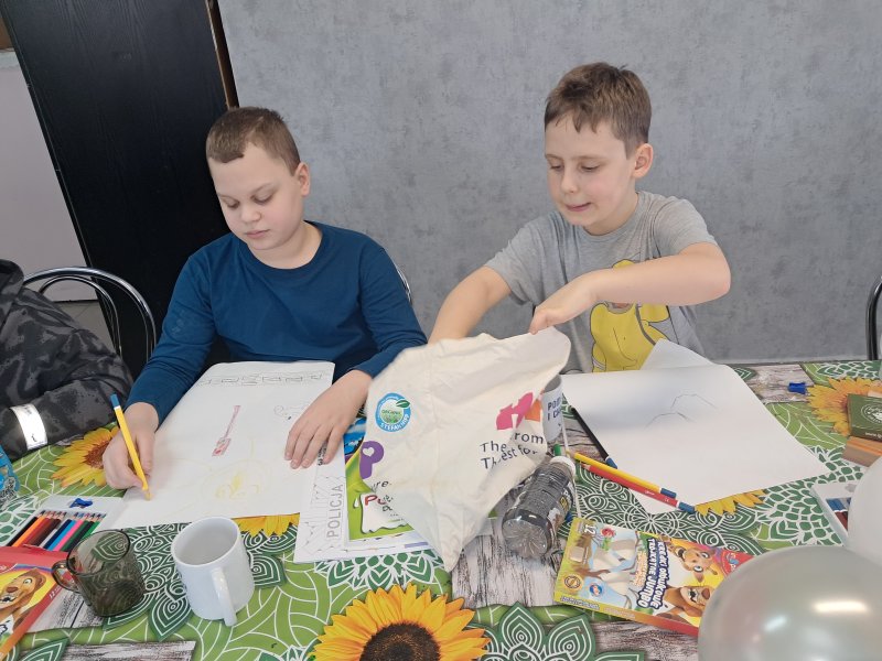 Zdjęcie przedstawia dzieci siedzące przy stoliku w świetlicy w trakcie zajęć plastycznych  