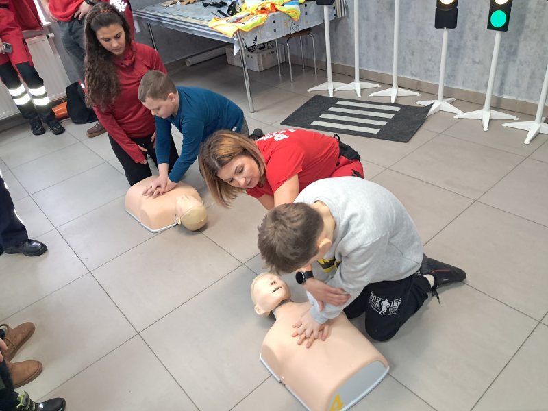 Zdjęcie przedstawia uczestników zajęć w trakcie nauki udzielania pierwszej pomocy z wykorzystaniem fantoma.  