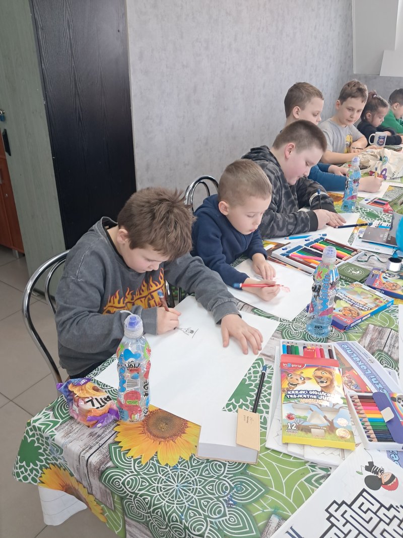 Zdjęcie przedstawia dzieci siedzące przy stoliku w świetlicy w trakcie zajęć plastycznych  