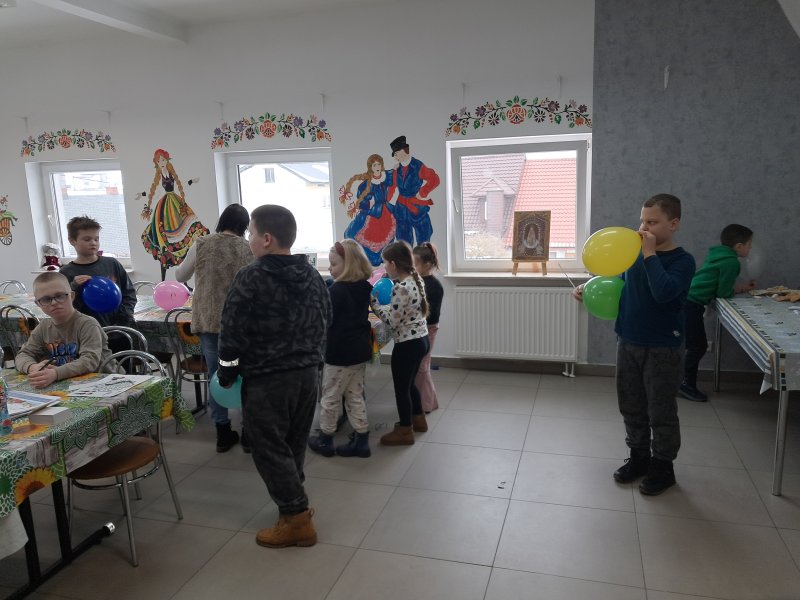 Zdjęcie przedstawia dzieci w trakcie zabawy z kolorowymi balonami  