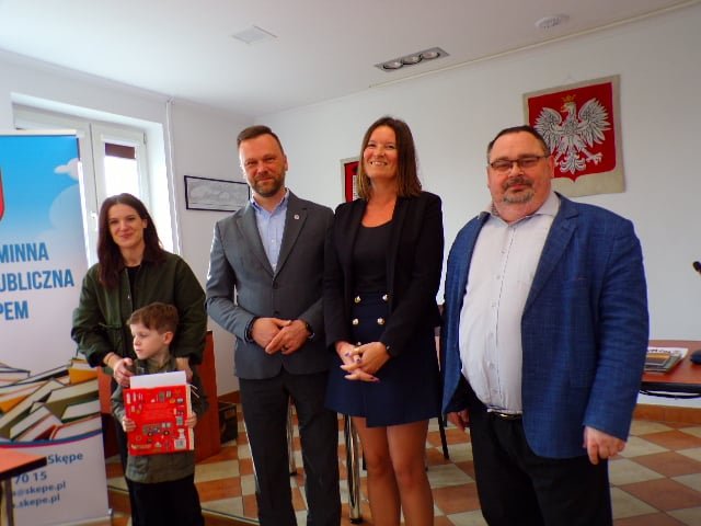 Zdjęcie przedstawia laureata konkursu stojącego z mamą i organizatorami w trakcie wręczenia nagród w sali konferencyjnej urzędu.  