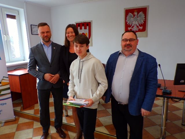 Zdjęcie przedstawia laureata konkursu wraz z organizatorami w trakcie wręczenia nagród w sali konferencyjnej urzędu.  