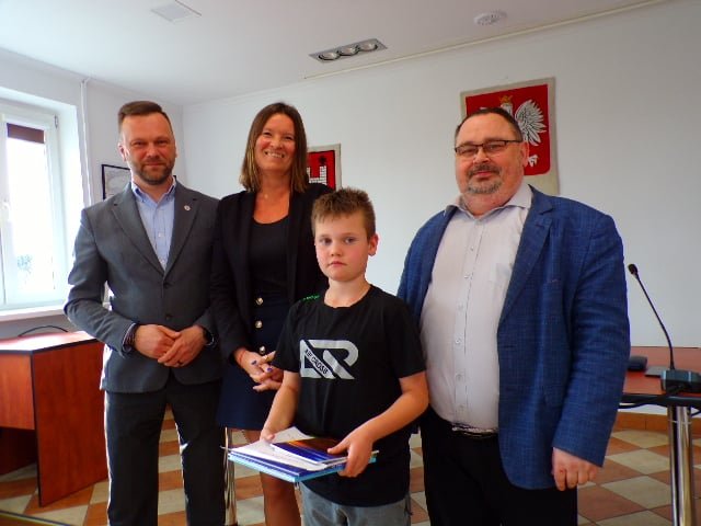 Zdjęcie przedstawia laureata konkursu wraz z organizatorami w trakcie wręczenia nagród w sali konferencyjnej urzędu.  