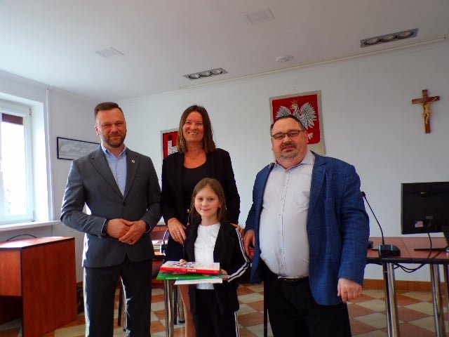 Zdjęcie przedstawia laureatkę konkursu wraz z organizatorami w trakcie wręczenia nagród w sali konferencyjnej urzędu.  
