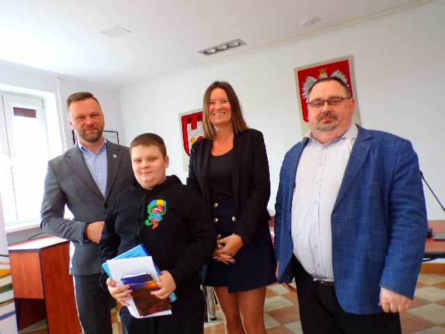 Zdjęcie przedstawia laureata konkursu wraz z organizatorami w trakcie wręczenia nagród w sali konferencyjnej urzędu.  