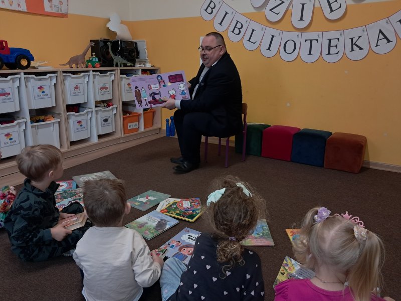 Na zdjęciu dyrektor skępskiej biblioteki prezentuje przedszkolakom w „Klubie Malucha” w Skępem bajkę „Kicia Kocia”  