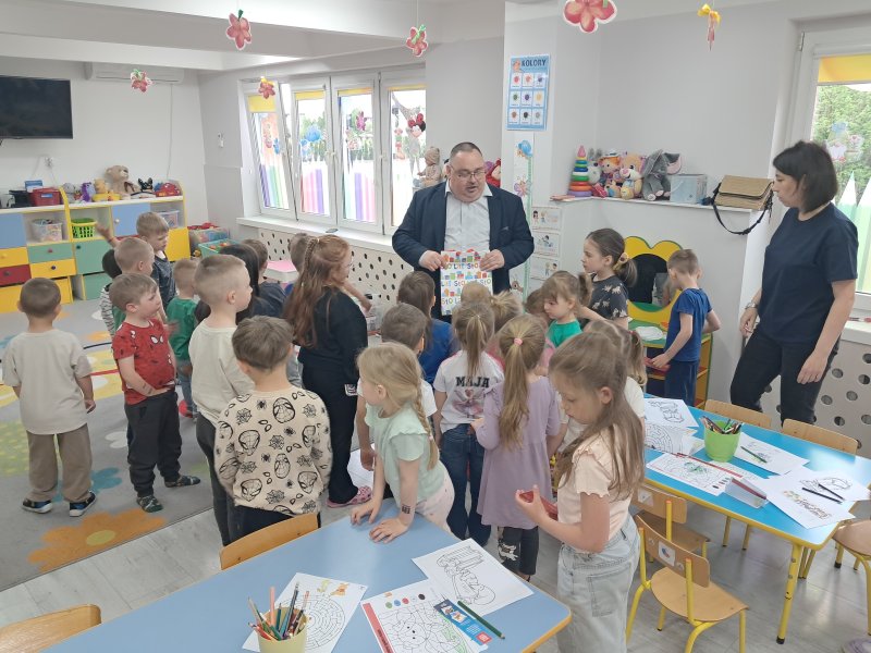 Na zdjęciu widać przedszkolaków z Publicznego Przedszkola w Skępem, przed którymi stoi dyrektor skępskiej biblioteki i wręcza im słodycze  
