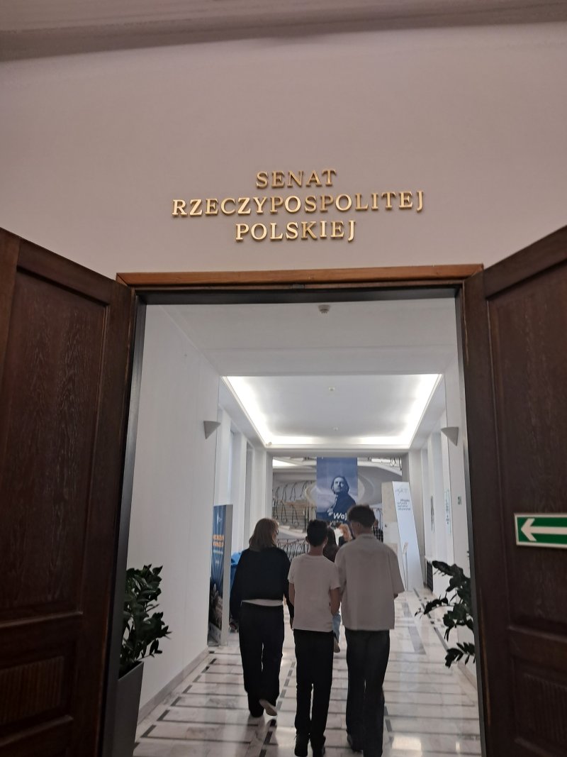 Fotografia przedstawia uczestników wycieczki w trakcie zwiedzania Sejmu w trakcie wejścia do Senatu RP  