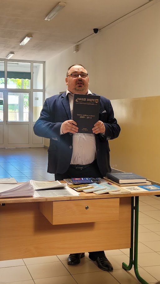 Zdjęcie przedstawia dyrektora biblioteki trzymającego w ręku oprawione w sztywną oprawę gazety „Nasze Skępe”  