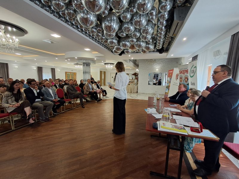 Zdjęcie przedstawia laureatkę konkursu stojącą przed uczestnikami konkursu i czytającą nagrodzony wiersz.   
