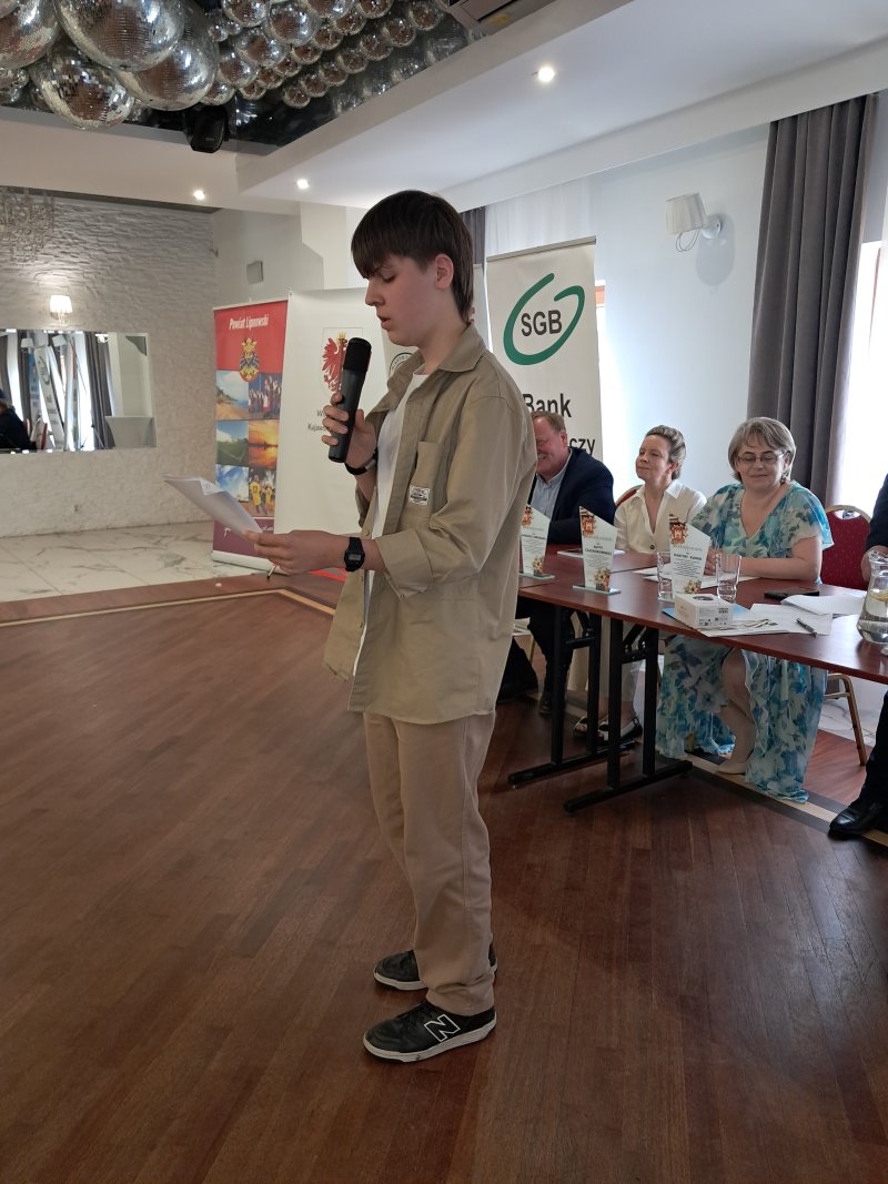 Zdjęcie przedstawia laureata konkursu czytającego nagrodzony wiersz  