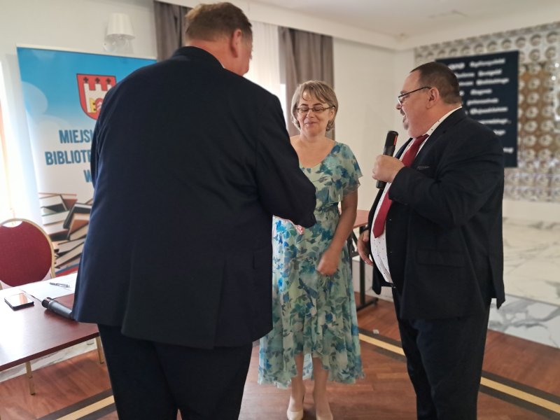 Zdjęcie przedstawia dyrektora biblioteki wręczającego podziękowanie członkowi Jury  