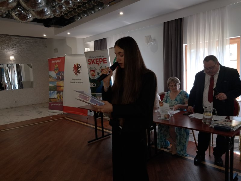 Zdjęcie przedstawia laureatkę konkursu czytającą nagrodzony wiersz  