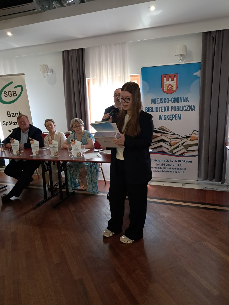 Zdjęcie przedstawia laureatkę konkursu czytającą nagrodzony wiersz  