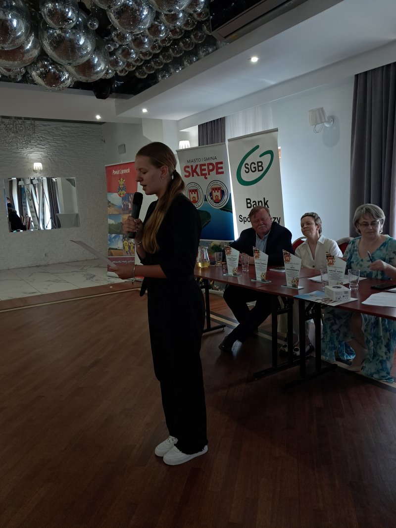 Zdjęcie przedstawia laureatkę konkursu czytającą nagrodzony wiersz  