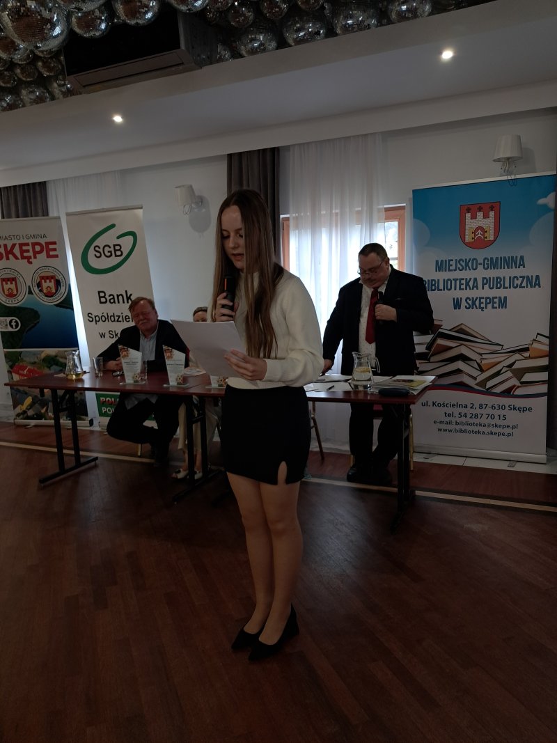 Zdjęcie przedstawia laureatkę konkursu czytającą nagrodzony wiersz  