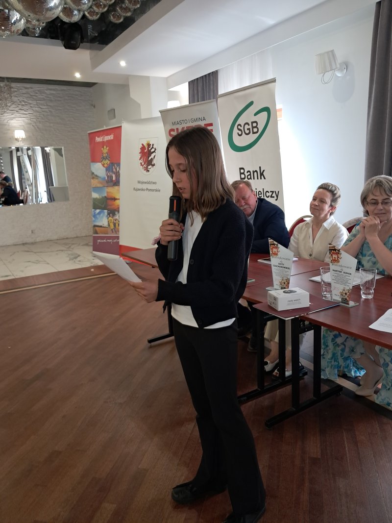 Zdjęcie przedstawia laureatkę konkursu czytającą nagrodzony wiersz  