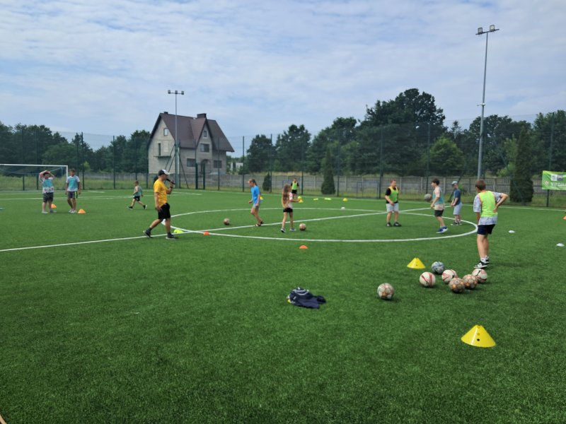 Zdjęcie przedstawia uczestników i animatora zajęć sportowych na Orliku w Skępem w trakcie zajęć  