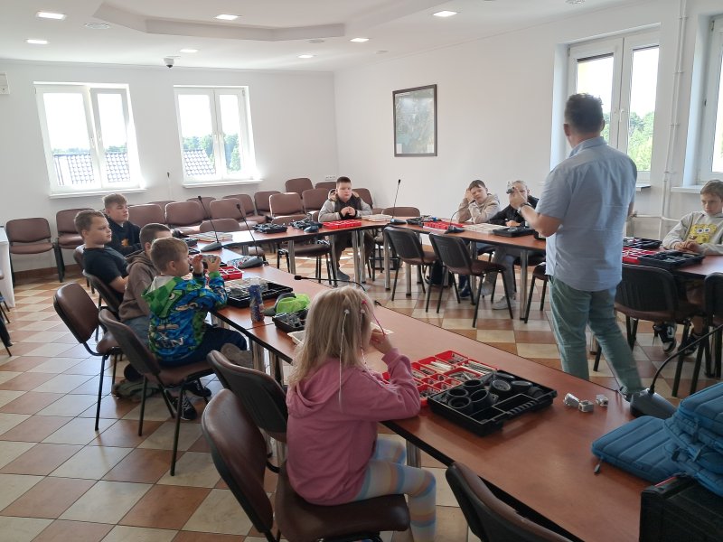 Zdjęcie przedstawia uczestników zajęć i instruktora robotyki w trakcie zajęć z robotyki w sali urzędu   