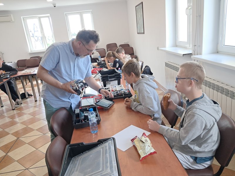 Zdjęcie przedstawia uczestników zajęć i instruktora robotyki w trakcie zajęć z robotyki w sali urzędu   