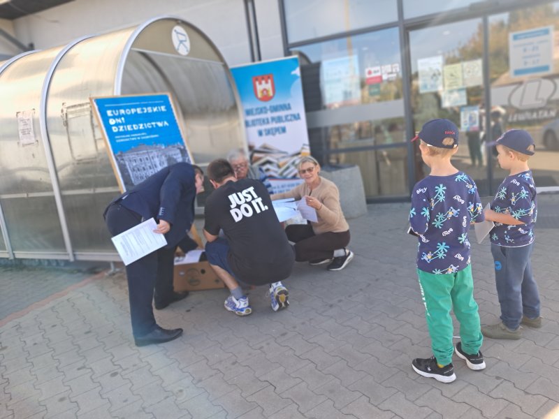 Widok ogólny na mieszkańców rozwiązujących quiz przed centrum handlowym   